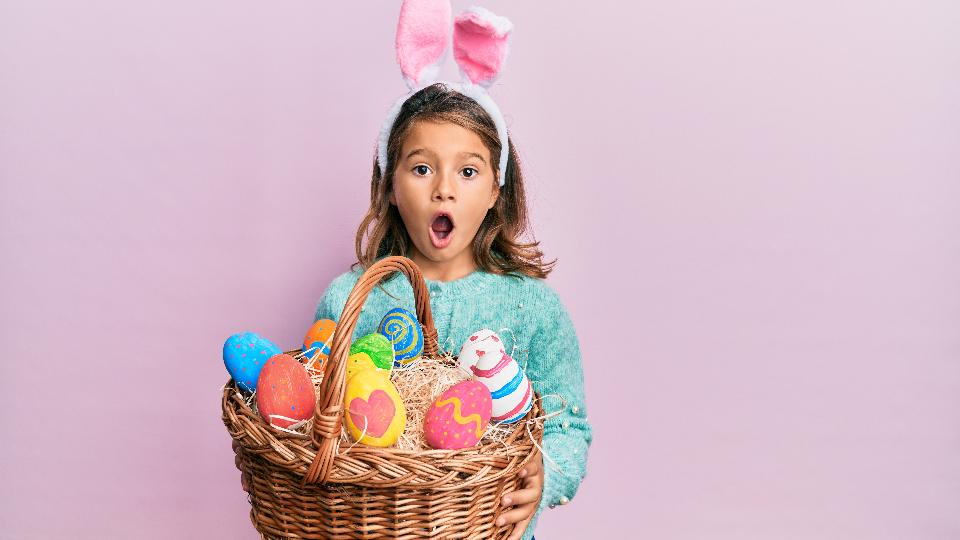 A surprised young girl holding a basket with Easter eggs in it